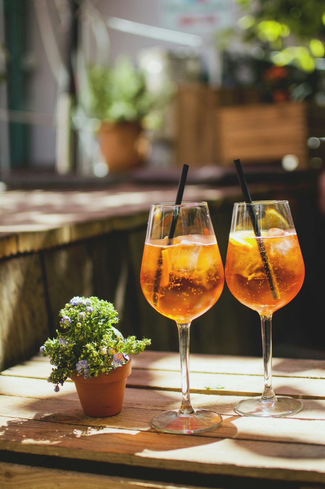 Two Aperol spritzes on a sunny patio at golden hour.