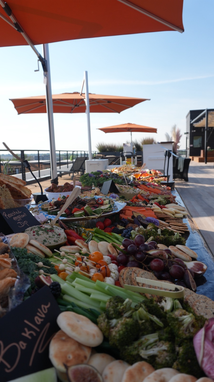 The Descanso plaza at golden hour with orange umbrellas and a long shareable spread.